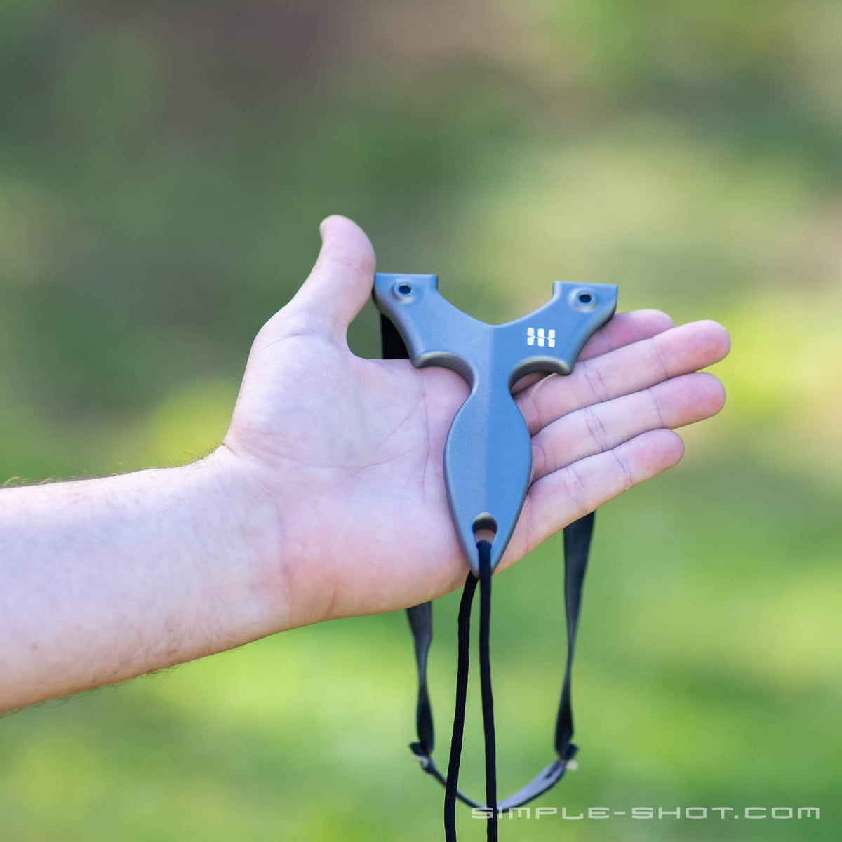Stylus Keeper PRO slingshot resting in an open hand outdoors