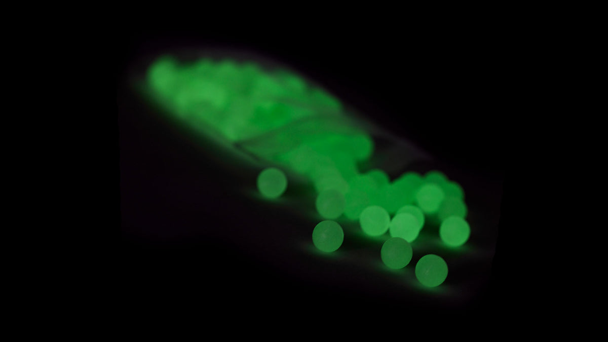 Glow-in-the-dark rubber slingshot ammo spilling from its box in the dark