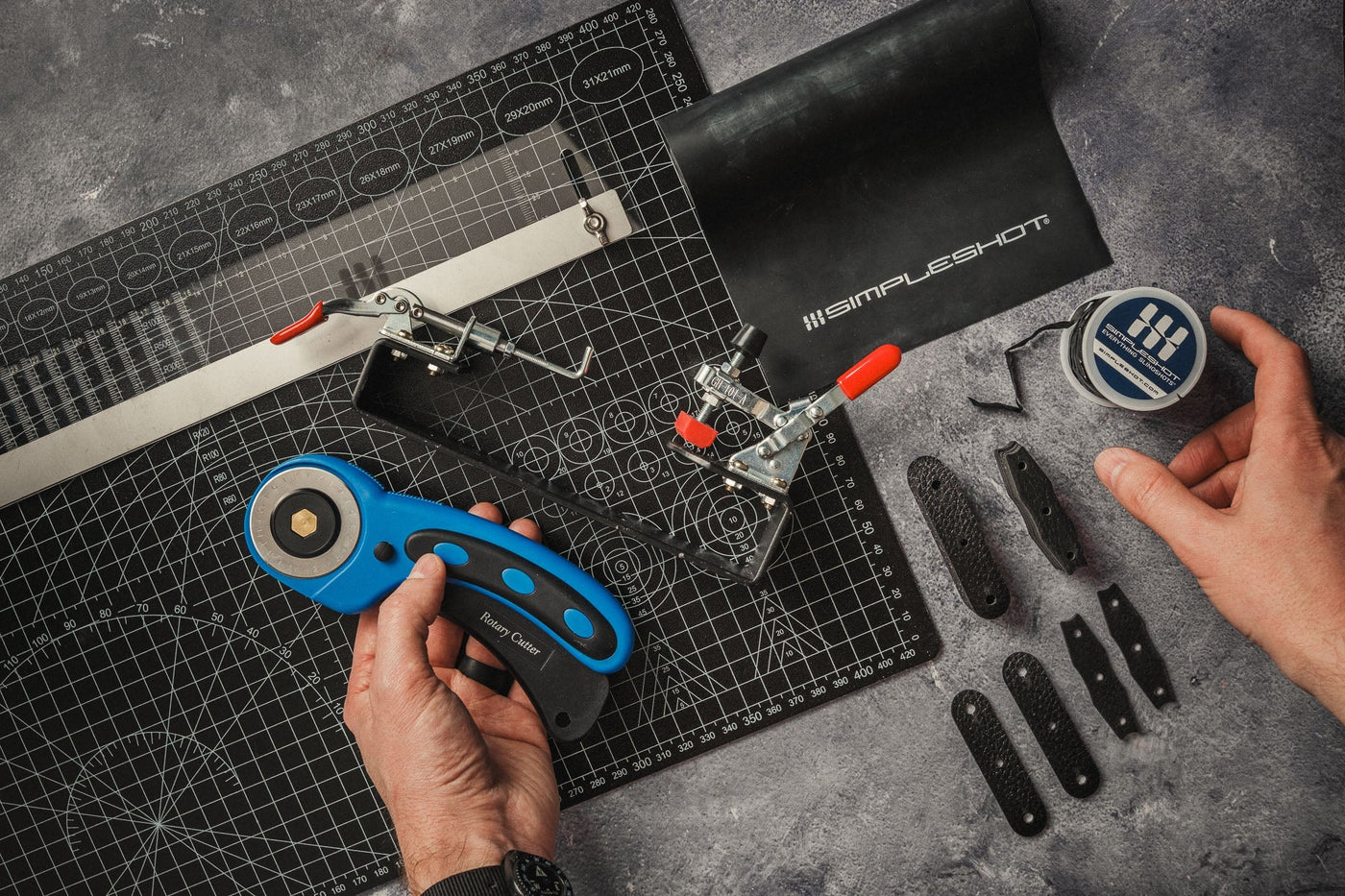 Cutting a slingshot bandset from a sheet of SimpleShot Black Premium Latex with a rotary cutter, taper ruler, and band tying jig