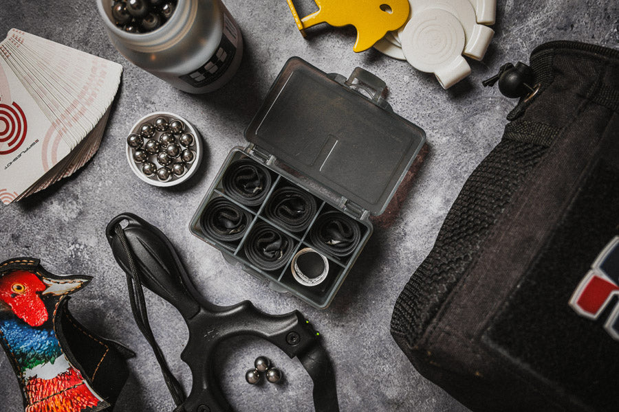 Heavy Duty flat bands flat-lay with slingshot, steel ammo, and a hunting pheasant pouch