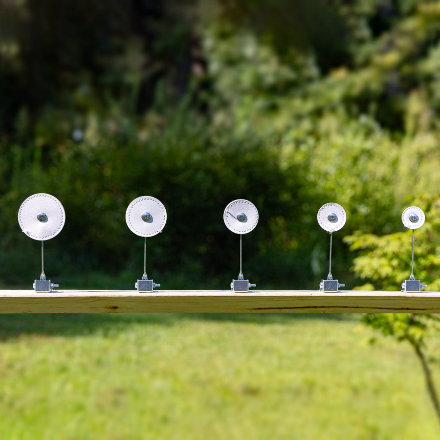Five SimpleShot self-resetting knockdown targets in a row on a beam outdoors