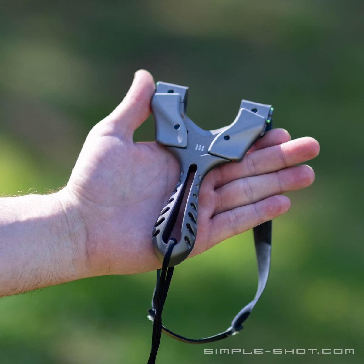 Axiom X slingshot in gray resting on an open hand outdoors