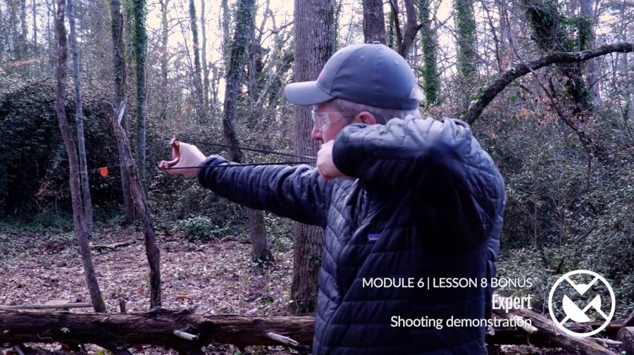 Foundations Online Course lesson: instructor shooting a slingshot in the woods