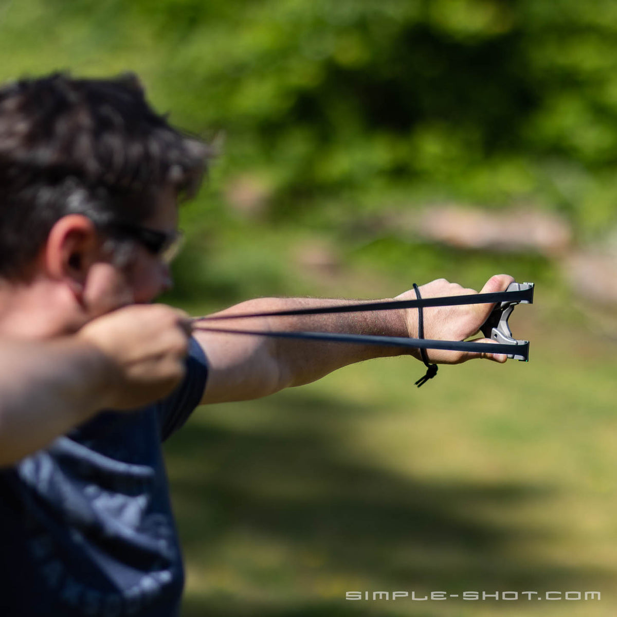 Man aiming the Axiom X slingshot at full draw outdoors, side view