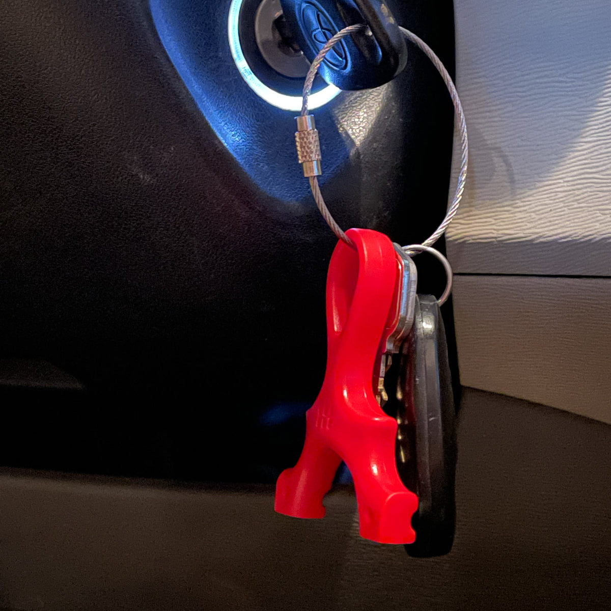 The Scout Keychain in red hanging from car keys in the ignition
